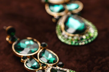 Luxury earrings with green gemstones on the brown velvet background
