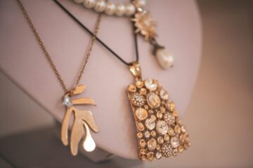 Amaranth dressing room boutique copy space boudoir table peach ecru apricot.Elegance interior with console table lavender blush modern in coral puce soft-hued neutral.Beautiful art mannequin heads on wardrobe shelves with beads from platinum silver for stylish fashion girl fashionista jewelry various set holders with gold chain jewelry.?lose-up beautiful jewelery diamonds pearl necklace earrings rings bracelets in jewelry box.Paper bag Chanel shop shopping on women table near mirror and candles